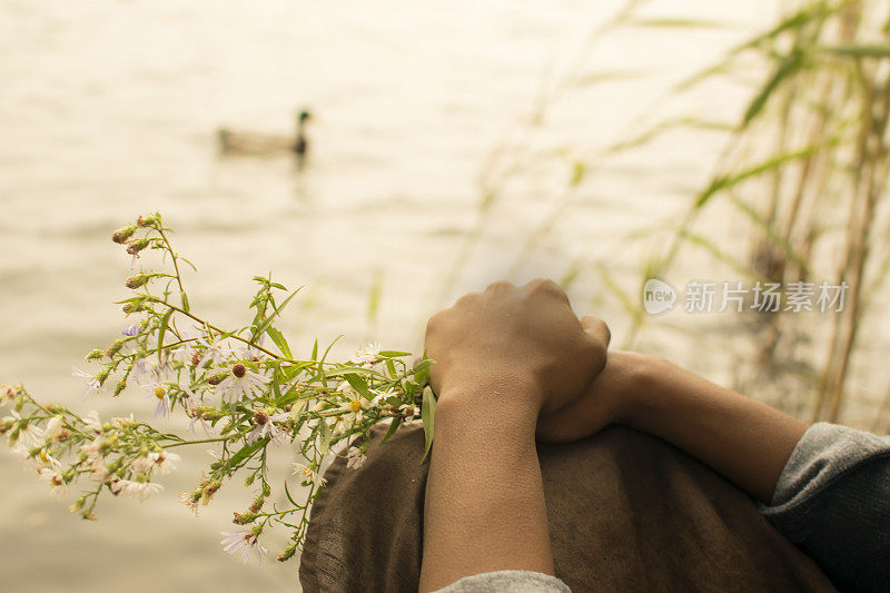 一位非裔美国妇女在池塘边捧着花