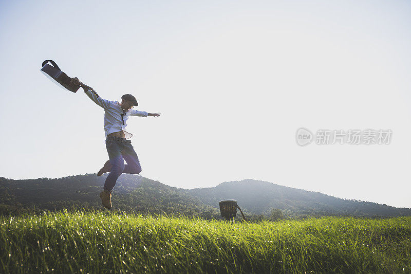 年轻有权势的男人拿着吉他在球场上跳来跳去