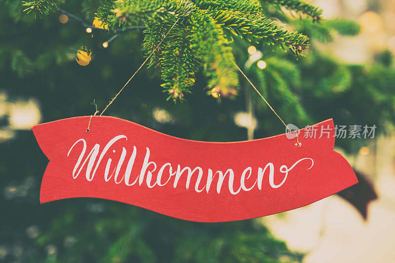 克拉科夫的圣诞树上挂着一块牌子，上面写着欢迎的字样，翻译成德语