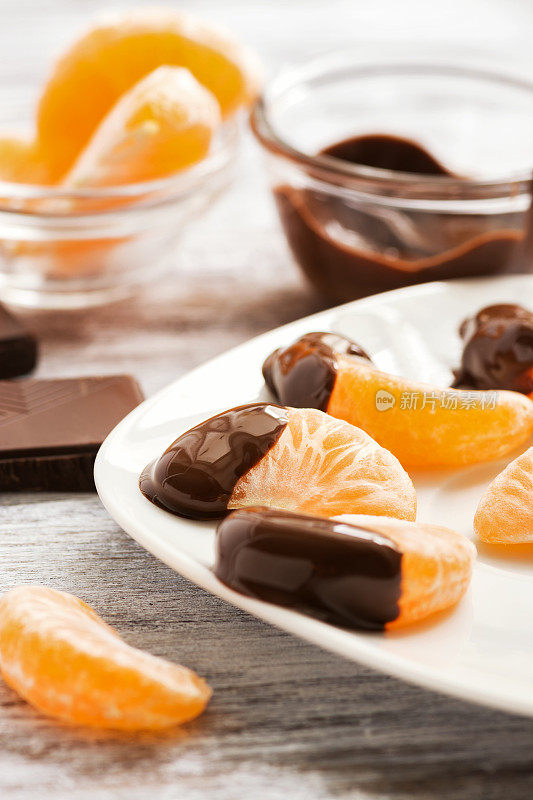 用液体巧克力裹着的桔子片盛在一个白色的盘子里。有选择性的重点。