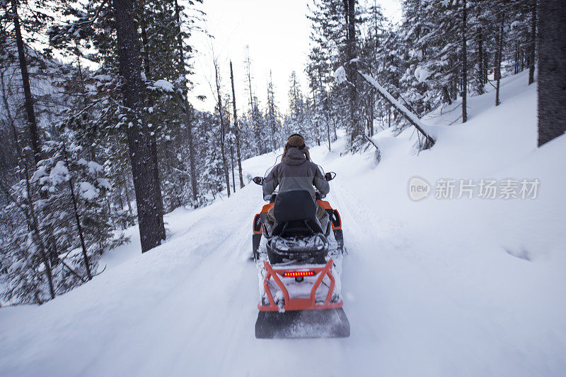 在冰霜森林中驾驶雪地摩托旅行的司机。