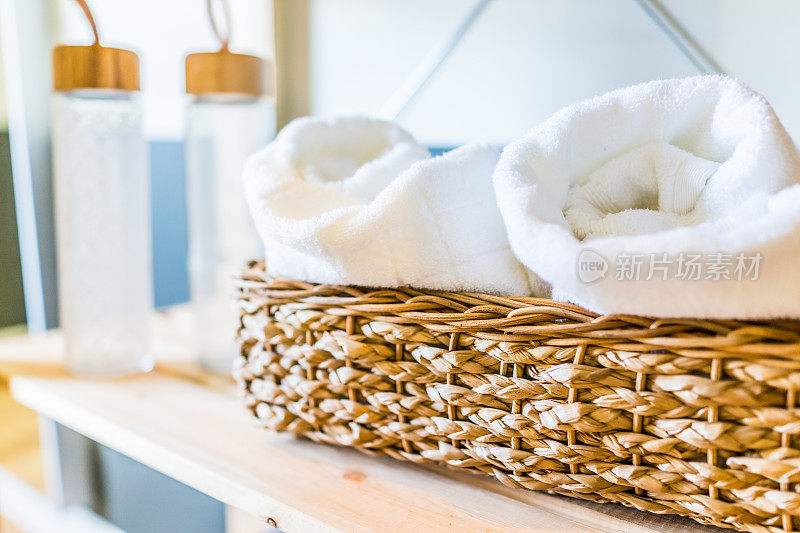 白毛巾编织篮和水瓶近距离在家庭健身房的架子上，在房子，家庭或公寓