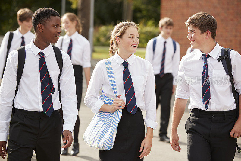 一群十几岁的学生在学校大楼外穿制服
