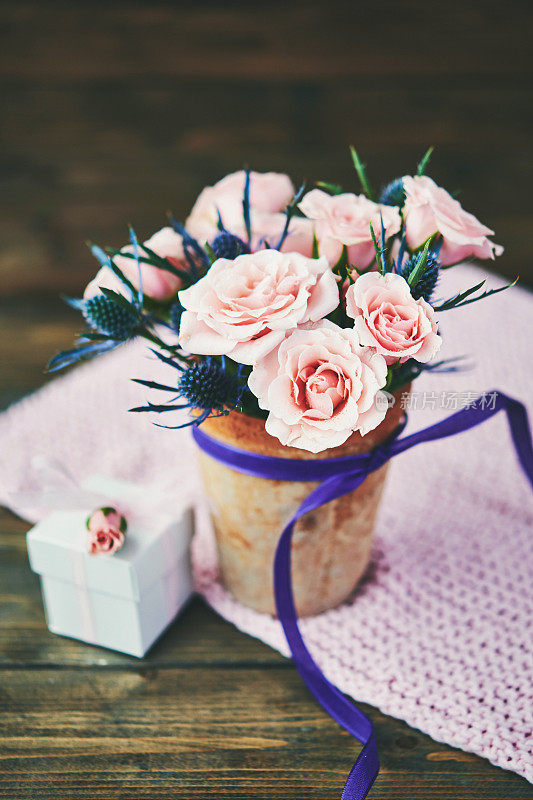 在乡村的背景下，带有粉红色玫瑰的母亲节花束和礼物