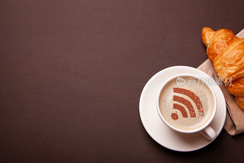 一杯泡沫上有WiFi标志的咖啡。免费接入互联网WiFi。我喜欢喝咖啡的时候吃牛角面包
