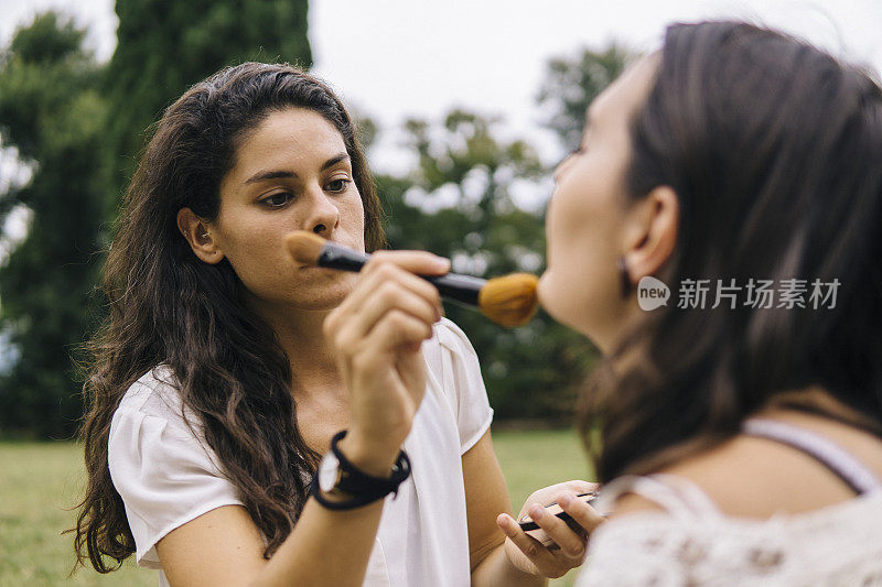 一对年轻女子在公园的户外化妆