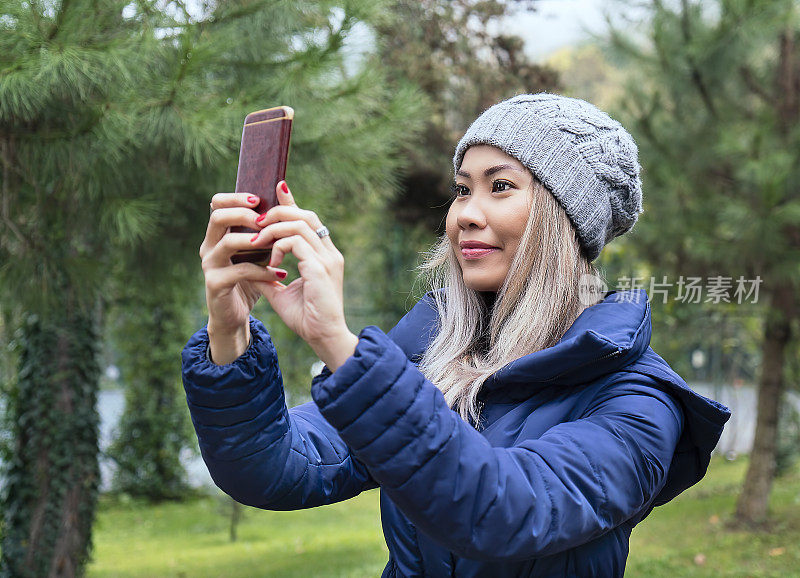 一名亚洲女性在公园里用手机自拍
