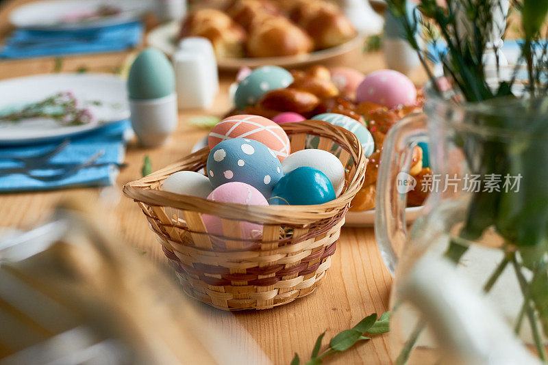 木制餐桌上装满复活节彩蛋的柳条篮子的特写