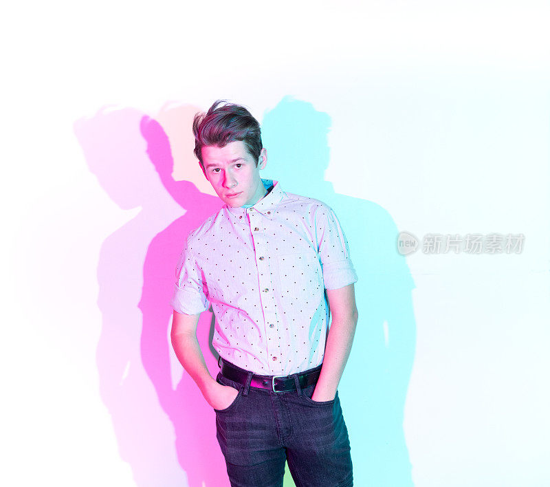 英俊的年轻人站在白色的墙壁和彩色的影子