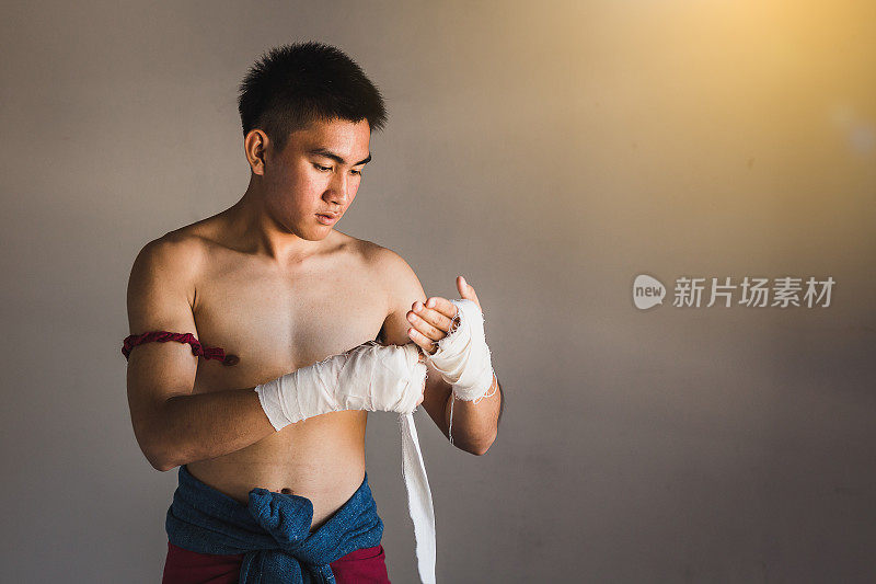 年轻的亚洲拳击手或泰拳战士准备和包裹他的手与拳击包装前训练或战斗，泰拳和武术概念