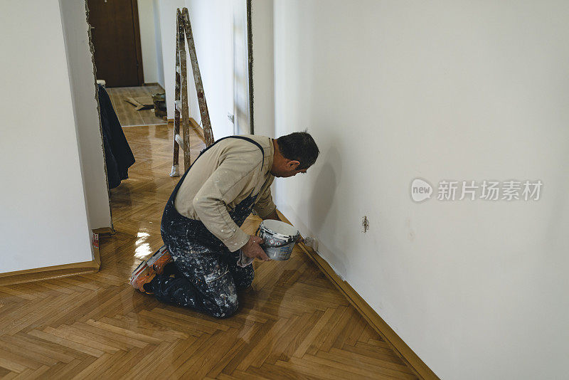 房屋油漆工正在用油漆刷刷白墙