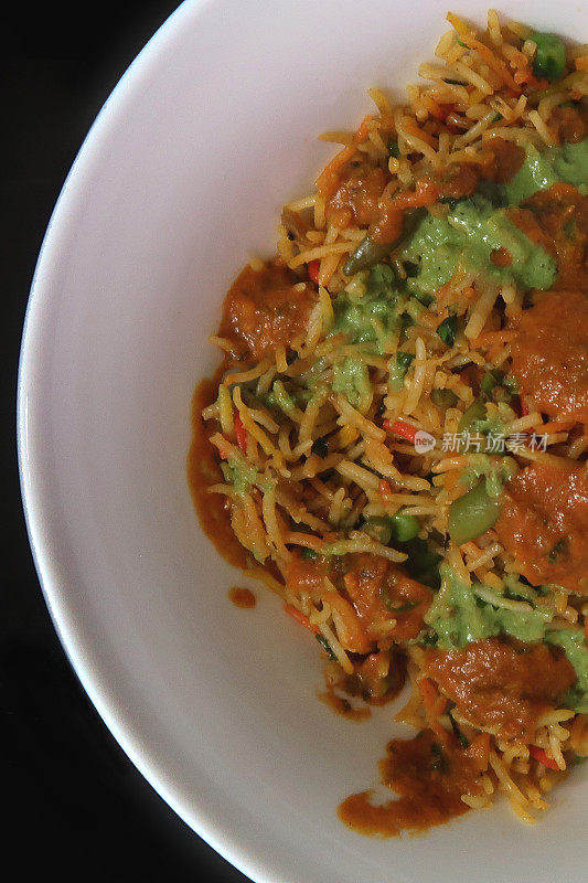 印度新德里外卖餐厅的蔬菜biriyani食谱没有鸡肉的咖喱菜，配上香料、肉汁酱、白肉饭、香菜香草、黑色餐桌、辣椒、法国青豆、绿酸辣酱