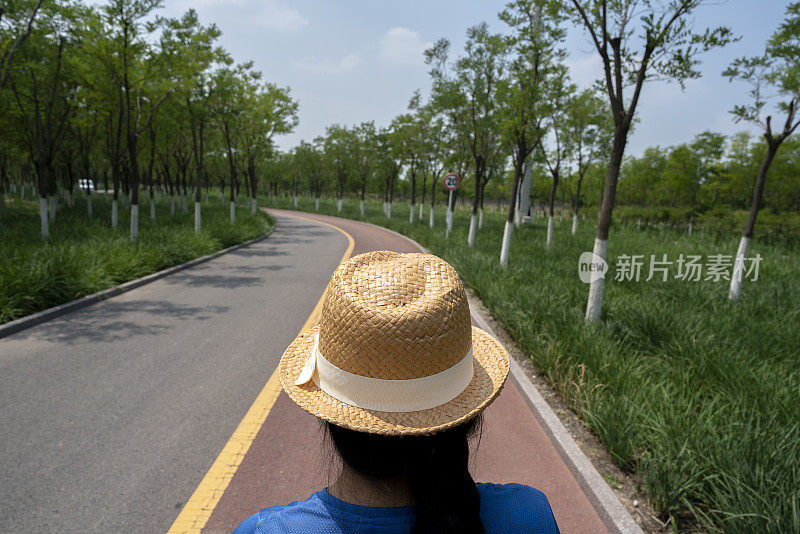 小女孩戴着太阳帽在公园里散步