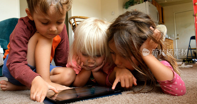 三个白人小孩，男女都在玩平板电脑