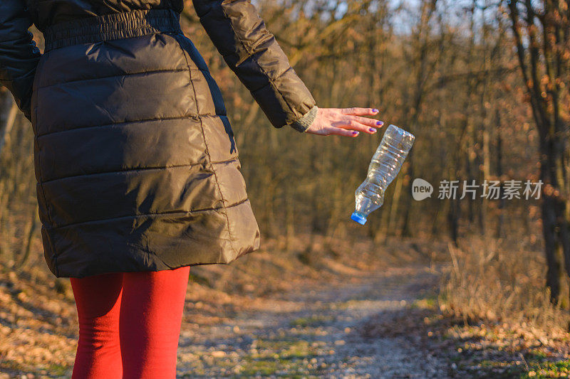 女人在大自然中丢弃塑料瓶。环境问题。