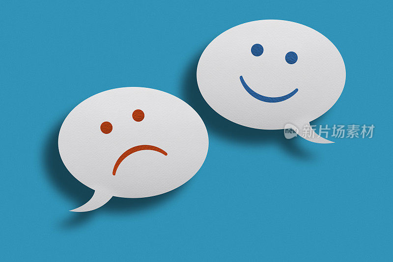 白色聊天气泡与快乐和悲伤的脸表情在蓝色的背景。