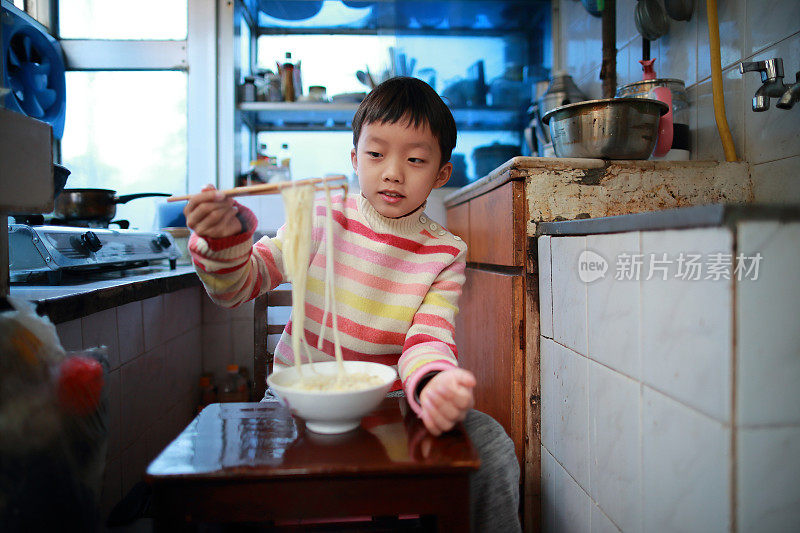亚洲男孩在旧厨房里吃饭