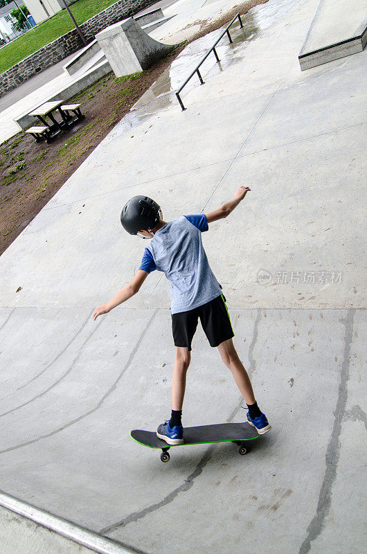 小男孩滑着滑板上斜坡