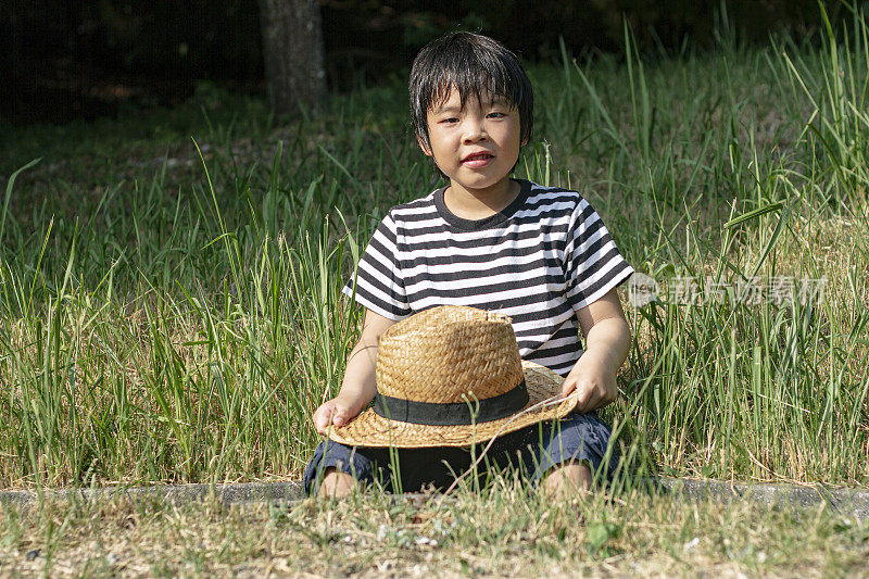 小男孩坐在草地上看着这里