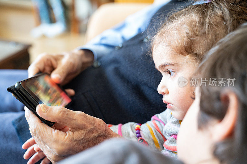 爷爷、孙子在用智能手机看电影