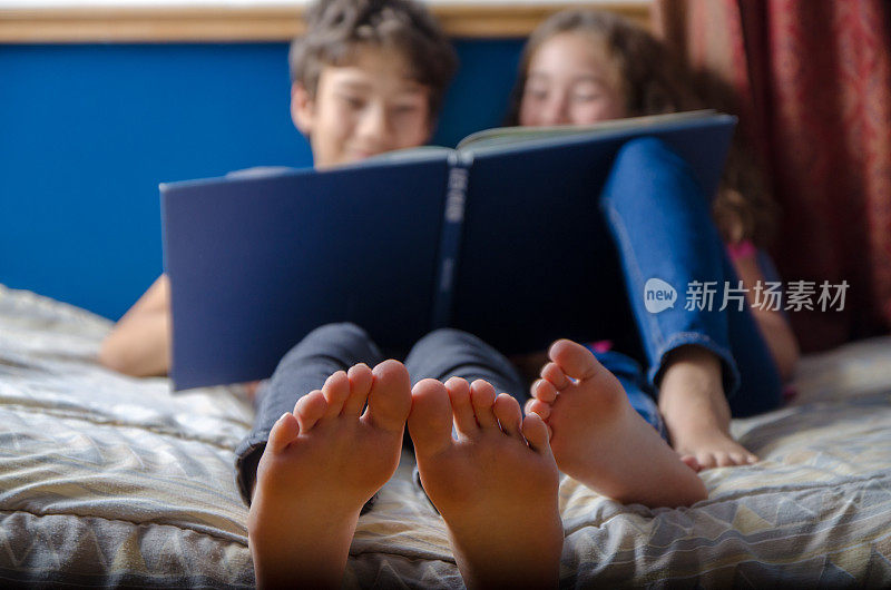 年轻的女孩和男孩在她的床上看书