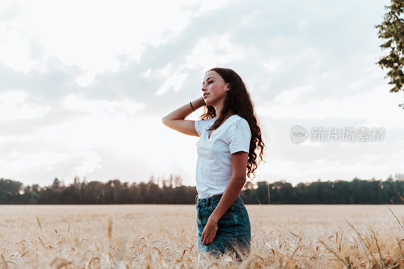 年轻女子在夏天的玉米地里望着地平线