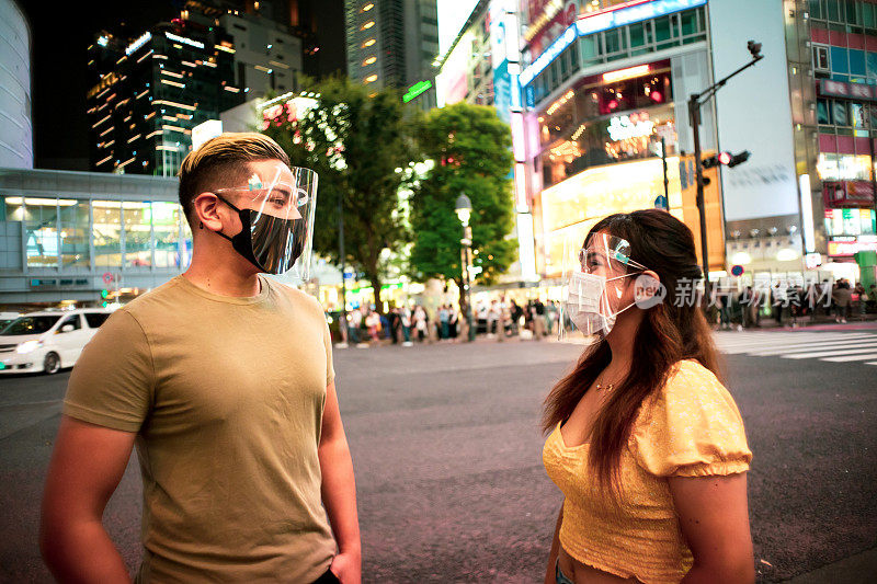 年轻男女的肖像，戴着面具和面罩在晚上的街道上