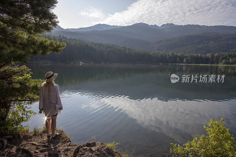 成熟的女人带着书和水瓶，停在湖边