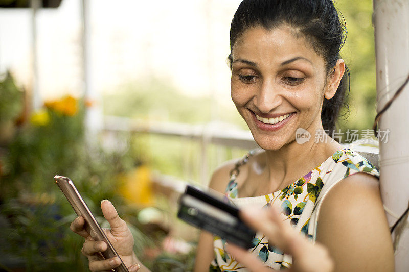 女人用信用卡和手机在网上购物
