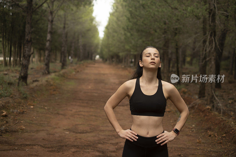 年轻的女运动员在森林里慢跑。晨跑者做体能训练。