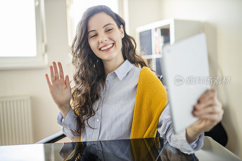 快乐的年轻女子在家庭办公室和朋友视频通话