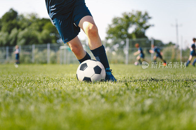 初级足球运动员踢球。足球前锋双腿训练游戏。运动运动员跑步球的特写图像。足球训练