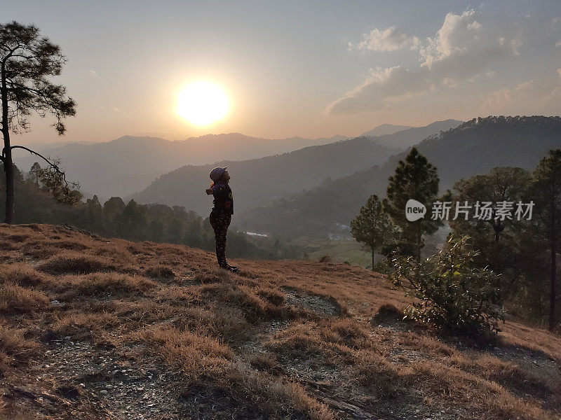 女孩在日落时欣赏风景优美的山景