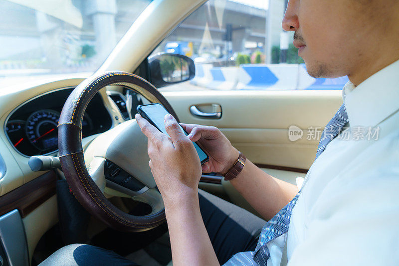 开车和打电话。心不在焉的司机用手机发短信。交通堵塞时用智能手机看短信的不负责任的人。汽车事故的概念。手里拿着智能设备。