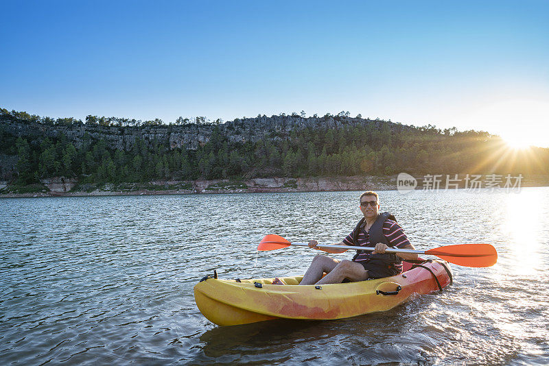 活跃的50多岁的成年男性在日落时分的加泰罗尼亚湖里划独木舟