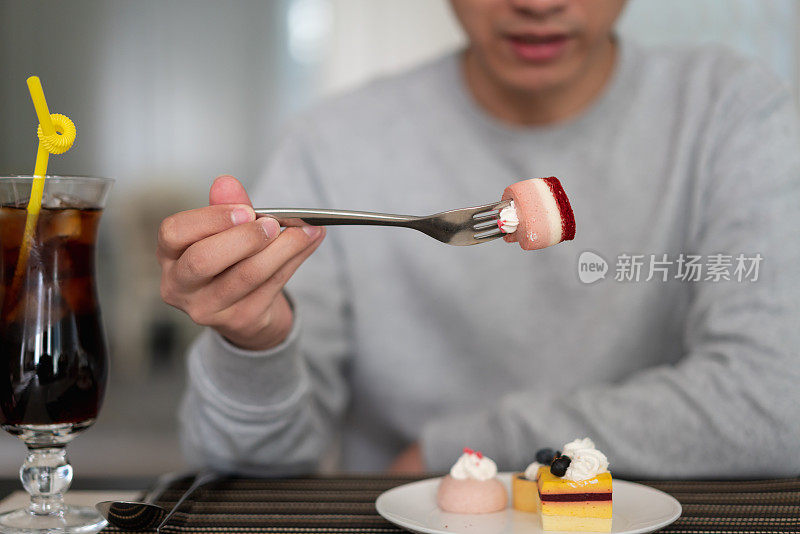 男人把叉子放在盘子上的甜点上，饭后准备甜点