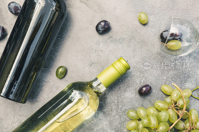俯瞰瓶红和白葡萄酒，绿藤，葡萄酒杯和成熟的葡萄在年份黑石桌子背景。酒店酒吧酒庄或品酒的概念