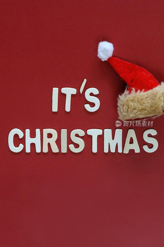 自制DIY简单的圣诞贺卡设计的图像，红色背景上的白色字母，手工制作的节日圣诞贺卡，这是圣诞讯息与圣诞老人的帽子，复制空间