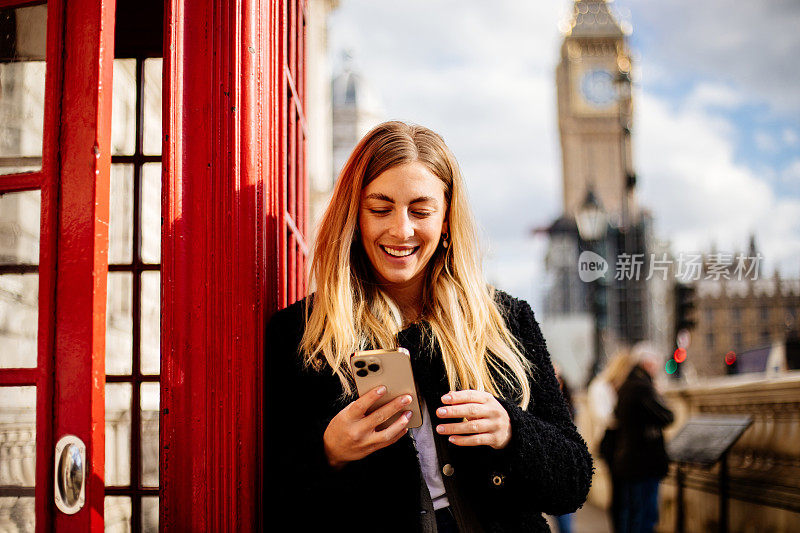 年轻美丽的女子在伦敦街头使用手机