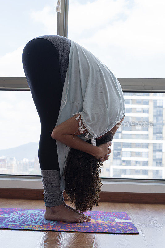一个拉丁女人正在她的公寓里做瑜伽练习
