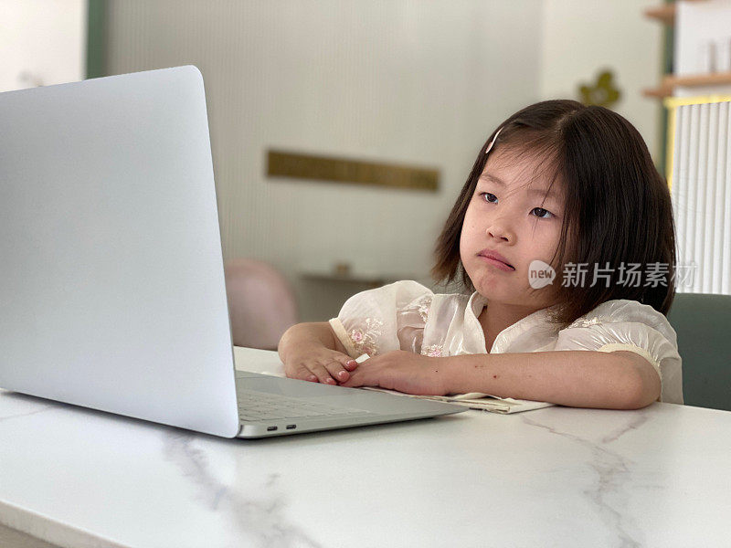 一个亚洲小女孩正在电脑上看视频