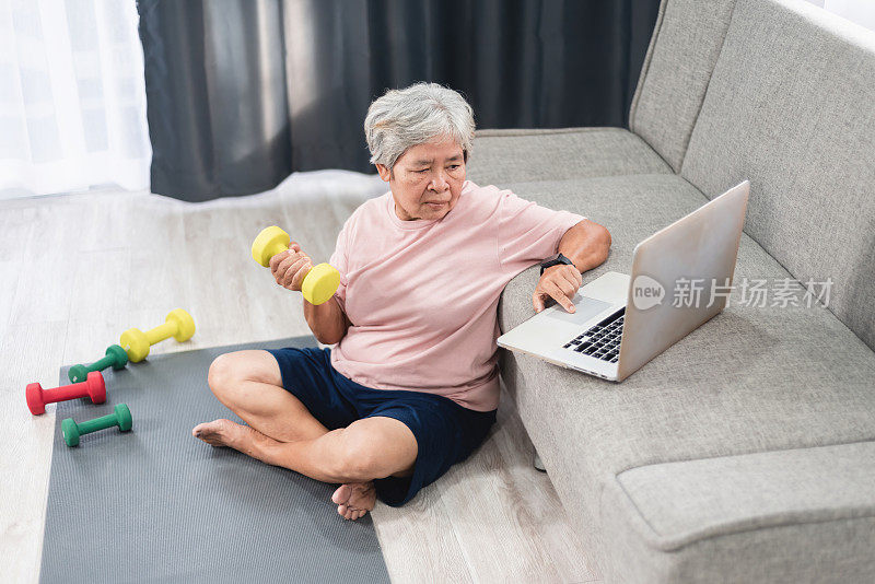 成人在线学习理念，亚洲老年妇女学习举哑铃。笔记本电脑上的视频指南。