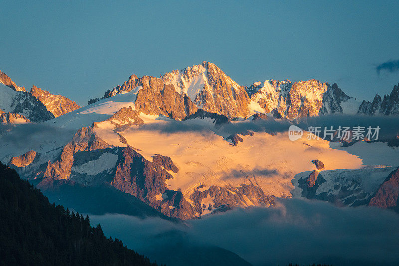 日落时美丽的山景，将岩石和雪变成橙色