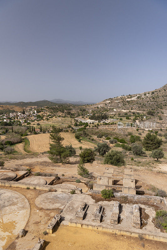 山坡上的历史黄金加工遗址的广视图，背景是村庄和山脉