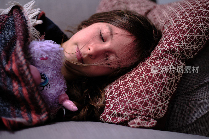 小女孩躺在沙发上打盹，抱着独角兽泰迪的肖像