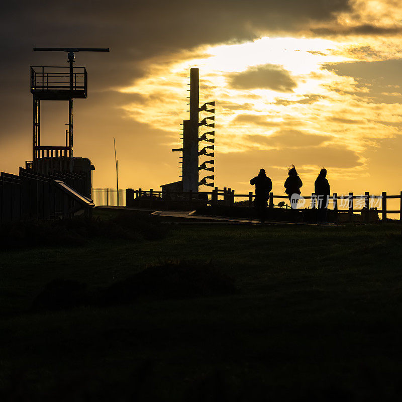 阿斯图里亚斯，坎塔布里亚海悬崖上的日落，人们在剪影中欣赏美景。