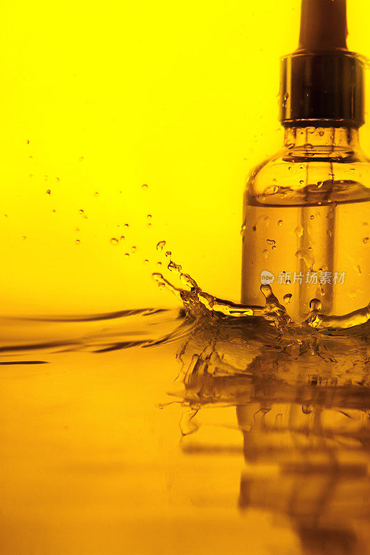玻璃瓶面部精华液，精油，精华液或维生素在金色背景上的飞溅水分离。
