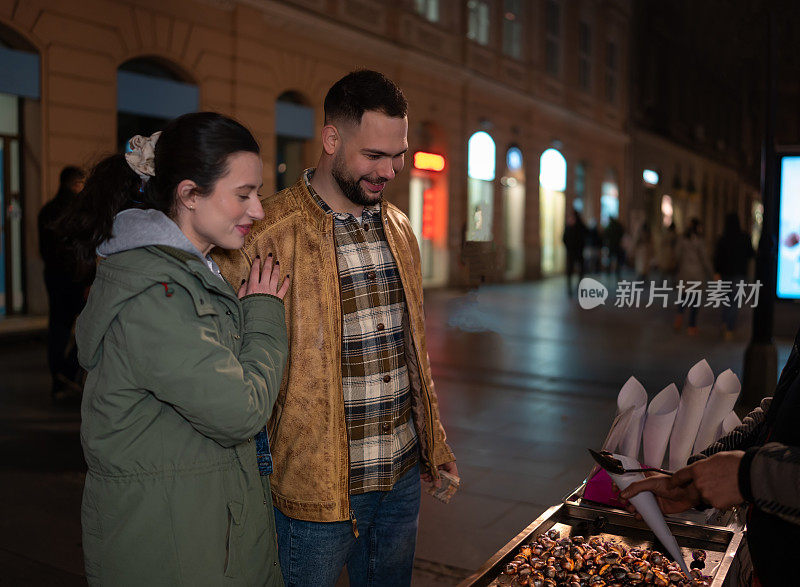 一对年轻夫妇在街上享用烤栗子