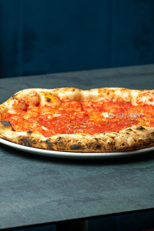那不勒斯番茄酱披萨，
披萨店餐桌上的大蒜和牛至