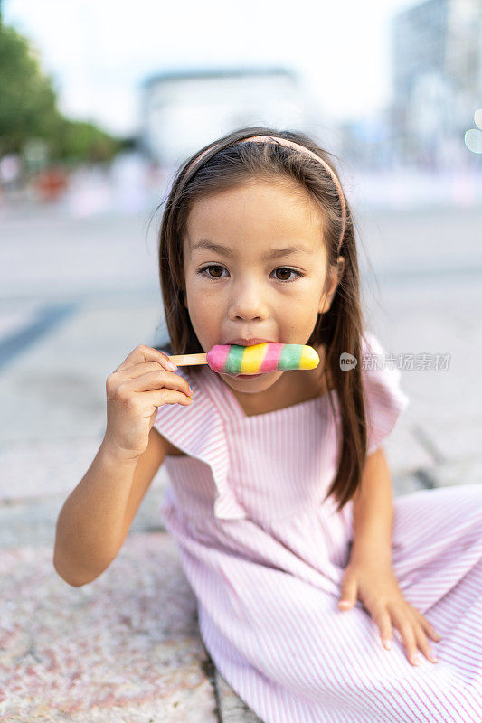 女孩在城市里吃着五颜六色的冰淇淋